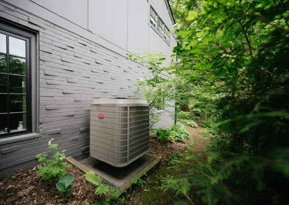 A heat pump condenser outside a home. 