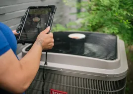 A HVAC technician assessing a heat pump.