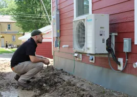 A contractor inspecting an air source heat pump