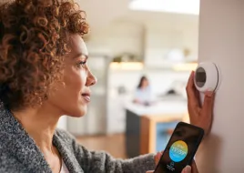 A homeowner adjusting a smart thermostat.