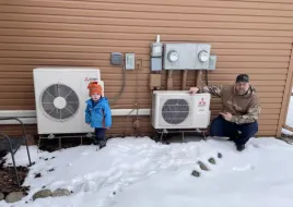 A family standing outside with their heat pumps during winter.