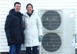 A family standing outside with their heat pumps during winter.